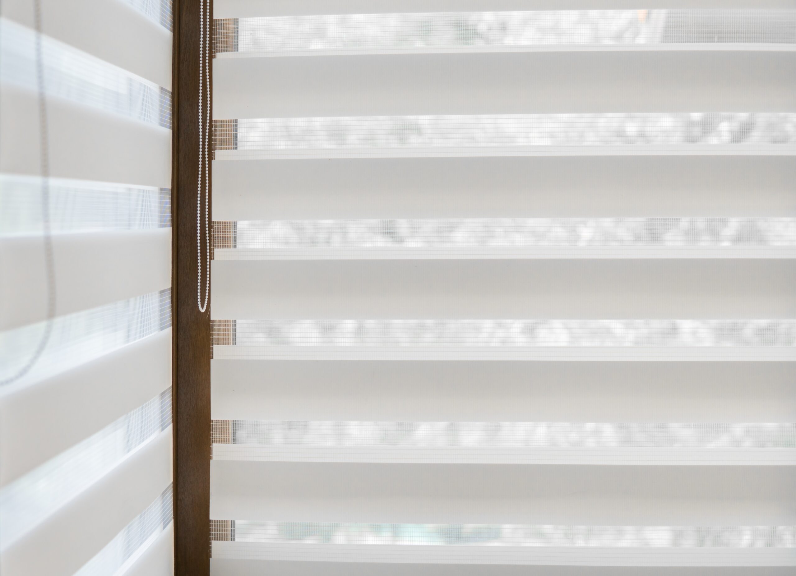 Details Of White Fabric Roller Blinds On The Plastic Window With Wood Texture In The Living Room.